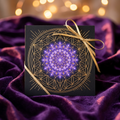 Magus Fawn gift card: a black card with gold sacred geometry and a glowing violet mandala, tied with a gold ribbon on purple velvet